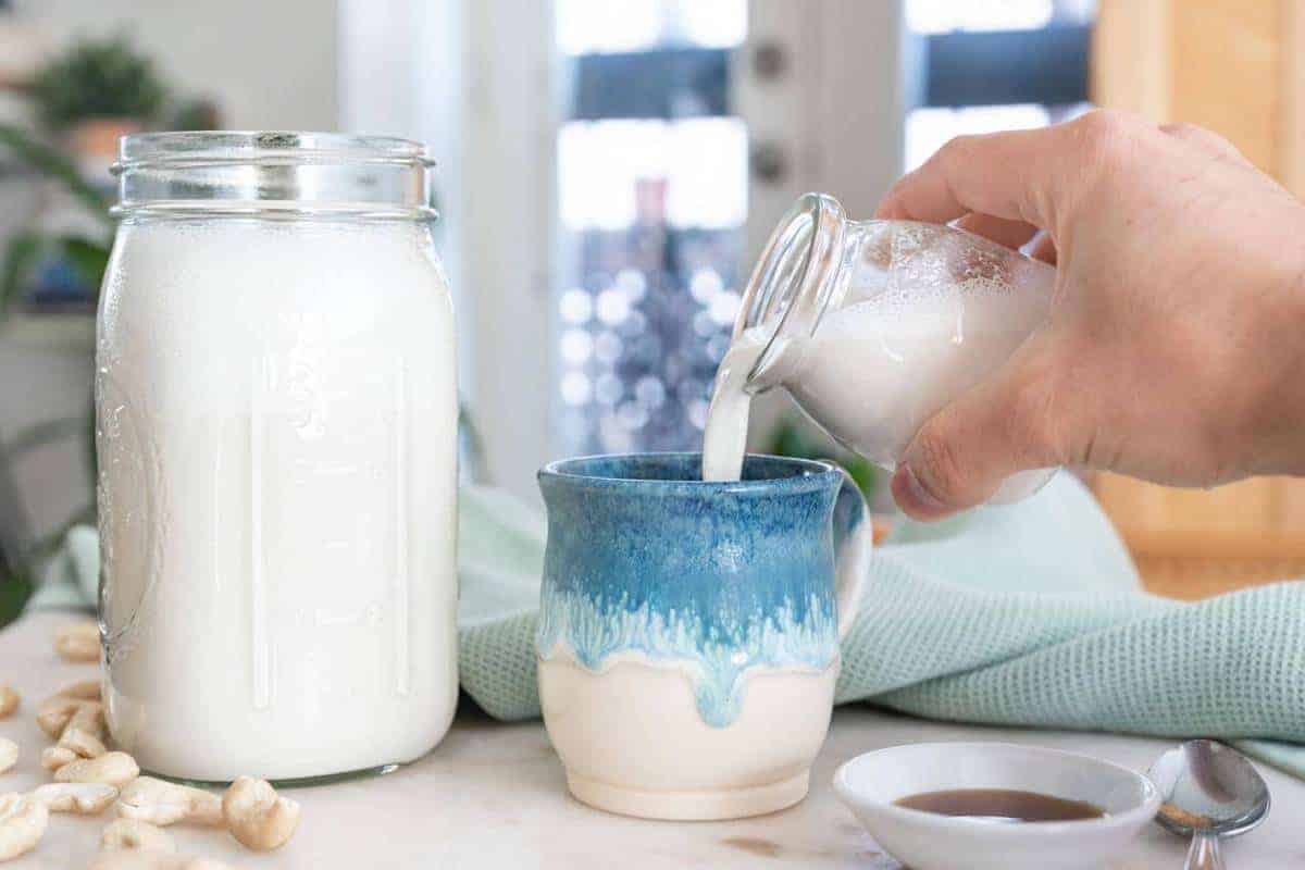 Mason Jar filled with Cashew Milk and a mug being filled