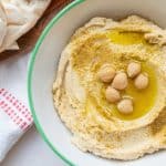 completed classic hummus in a bowl topped with oil and chickpeas