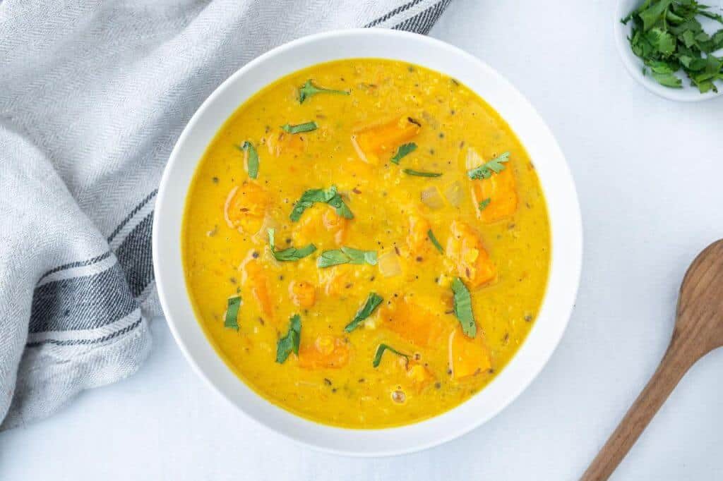 Creamy Curried Butternut Squash Lentil Soup in a white bowl with a white background