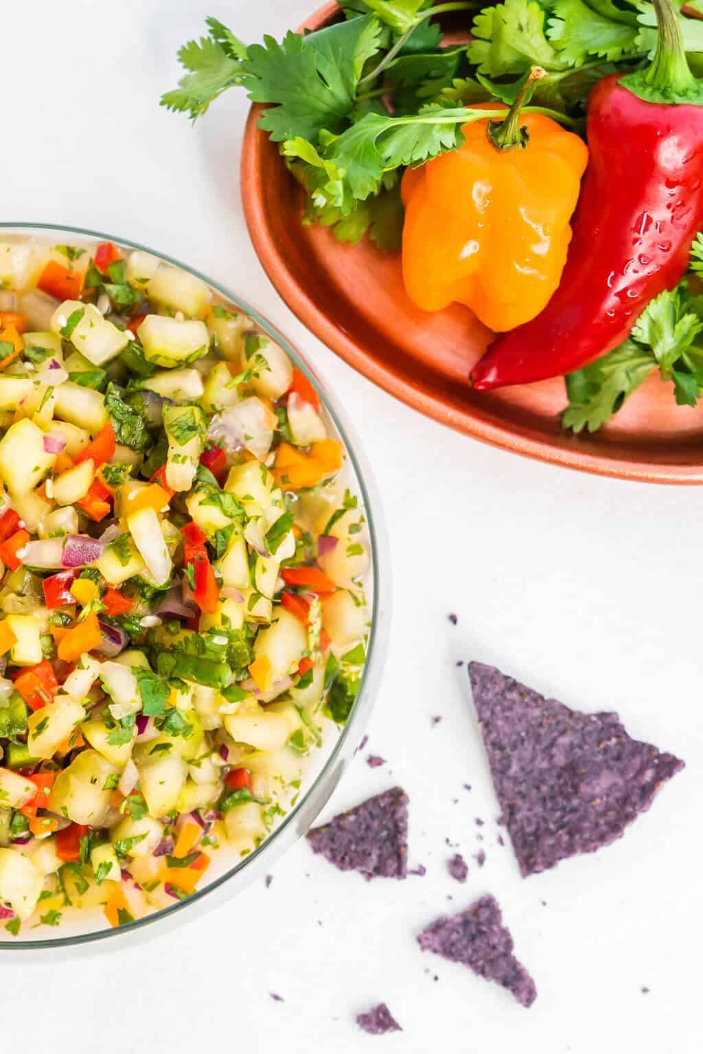 Cucumber salsa in a large bowl next to a platter of fresh peppers.