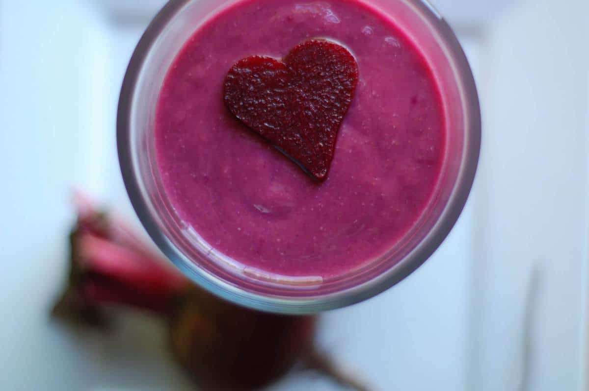 A heart of dark red smoothie topping a pink smoothie in a glass.