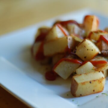 Cubed potato home fries on a white plate.