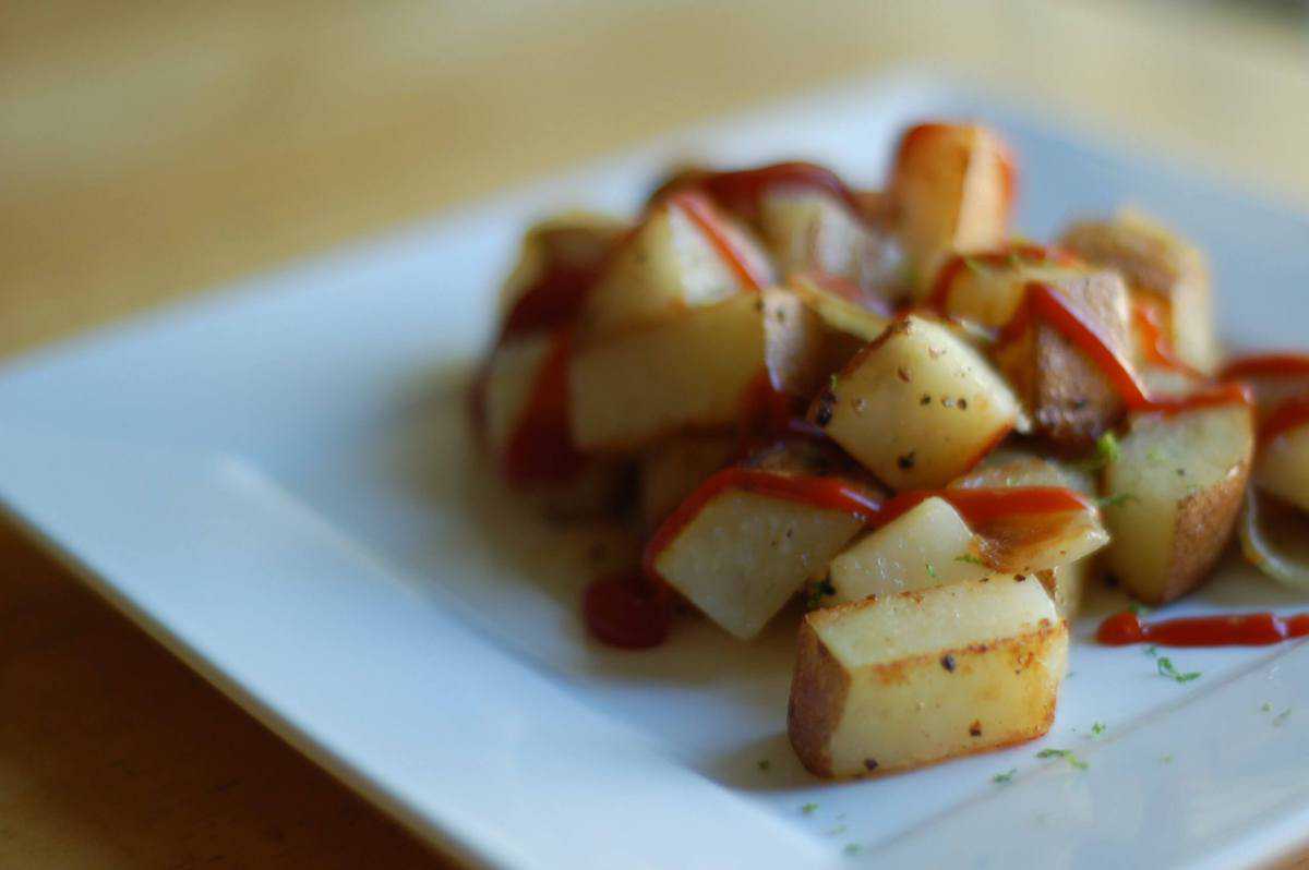 Cubed potato home fries on a white plate.