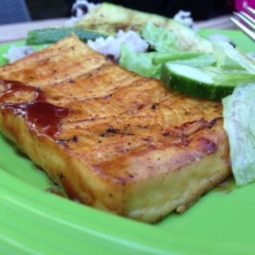 Grilled tofu block with salad on a green plate.