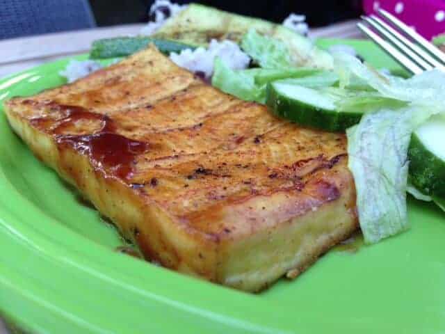 Grilled tofu block with salad on a green plate.