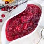 completed Homemade Cranberry Sauce plated in white bowl with lemon zest against white background