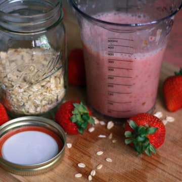 Jar of oats and jar of smoothie next to each other on a wood counter.