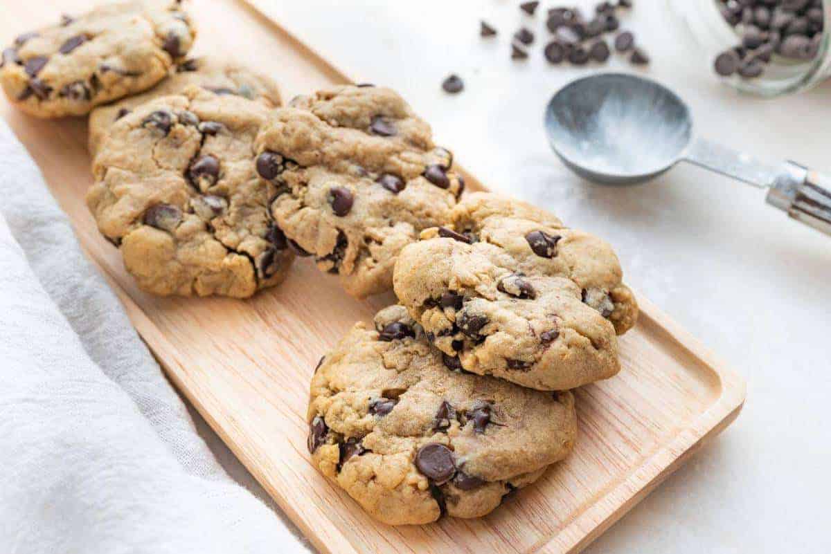four chocolate chip cookies on a brown tray with a white background
