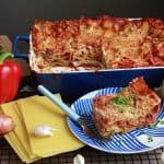 A baking dish of lasagna next to a slice on a plate.