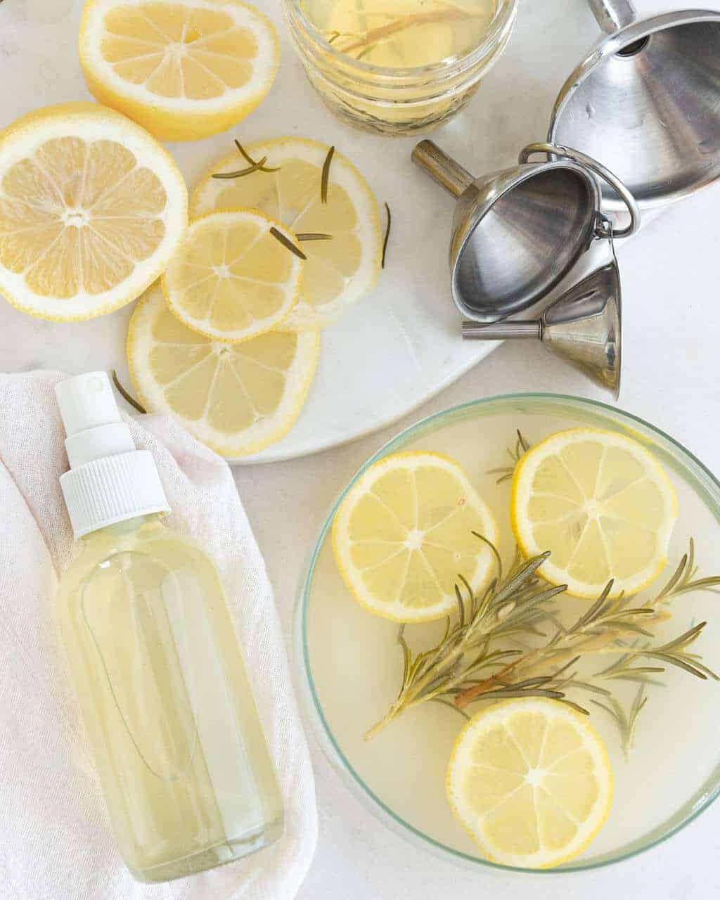 Lemon Rosemary room spray in a bottle next to sliced lemons.
