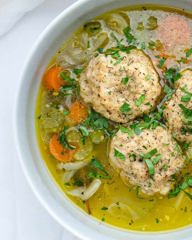 Matzoh Ball Soup in a white bowl on a white background