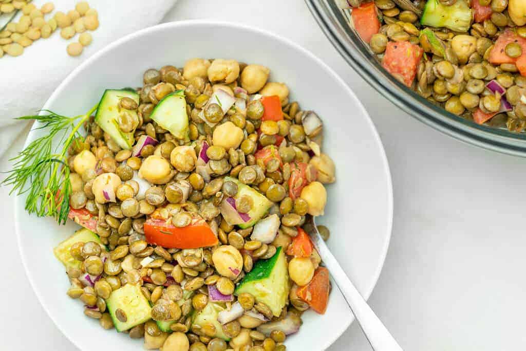 Close up of a white bowl filled with Mediterranean lentil salad.