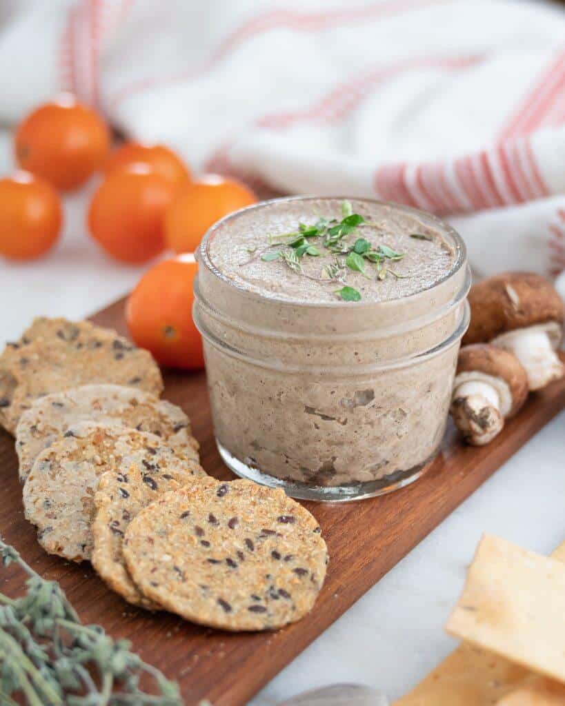 Mushroom Pate in a glass jar on a cutting board with ingredients in the background