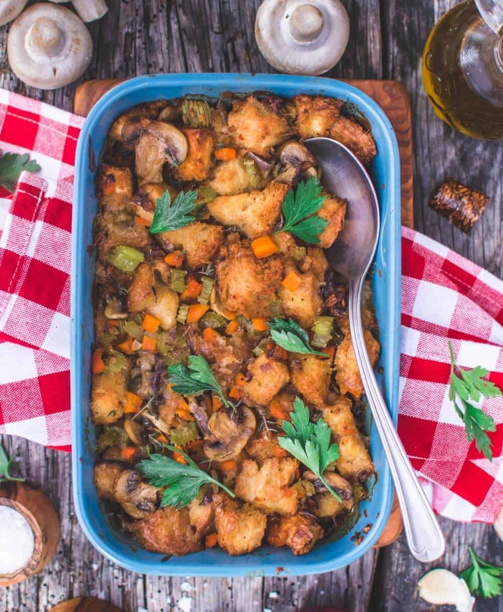 A casserole dish and serving spoon with vegan mushroom stuffing.