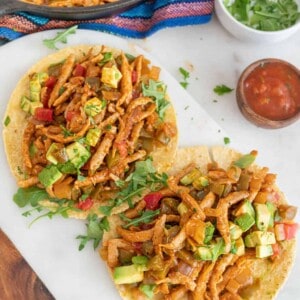 Plant-based tacos with toppings on a white plate.