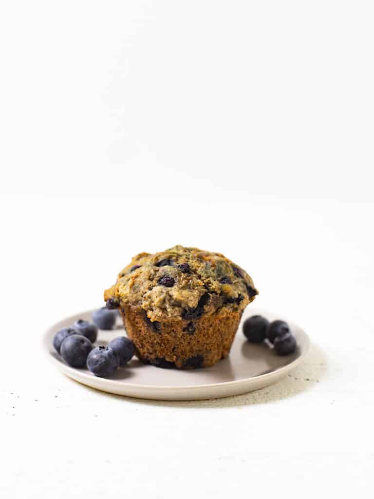 A single vegan banana blueberry muffin on a small white plate.