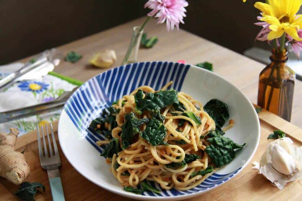 Peanut spaghetti with kale in a patterned bowl.