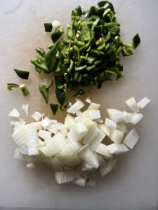 cut up onion and peppers against a white surface