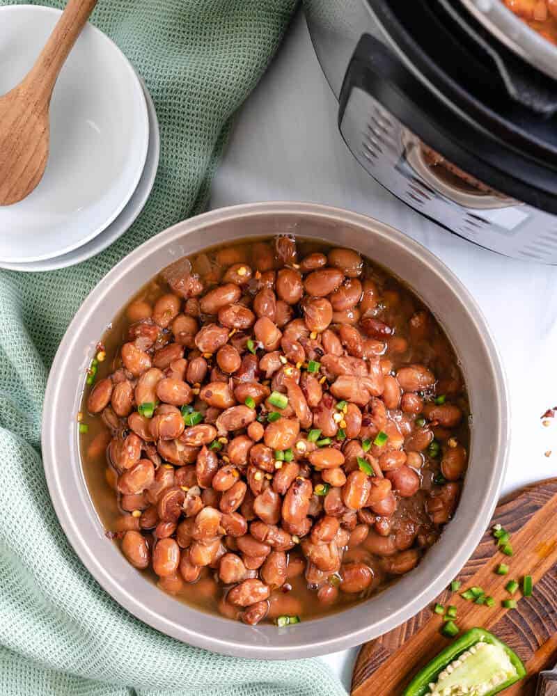 instant pot pinto beans in a bowl with ingredients, bowls, and an instant pot in the background
