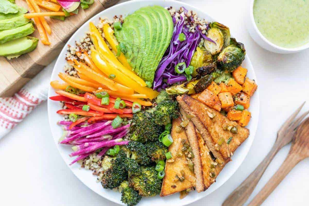 Bowl of colorful veggies with a small bowl of green tahini dressing