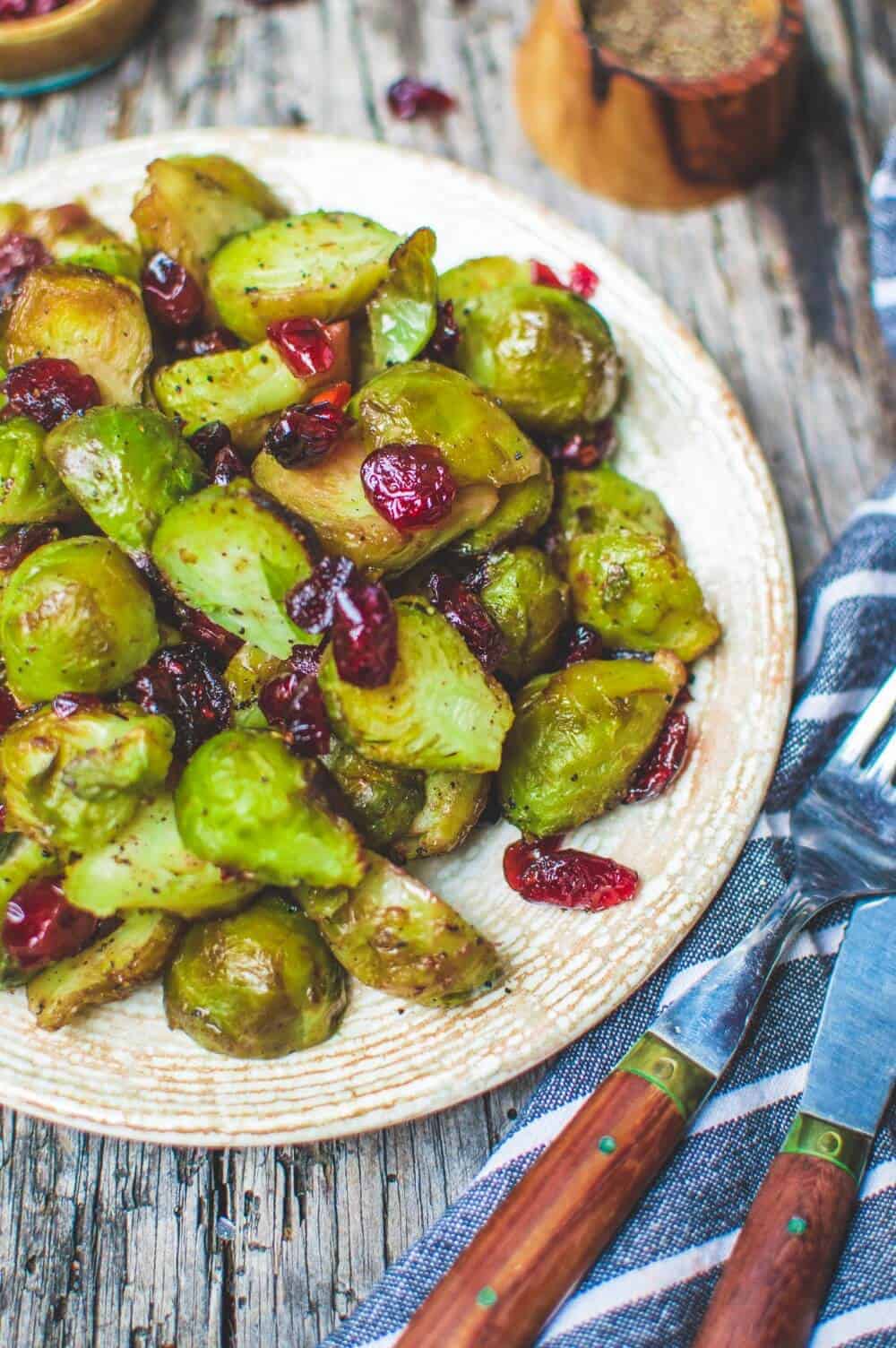 Roasted brussels sprouts mixed with dried cranberries on a white plate.