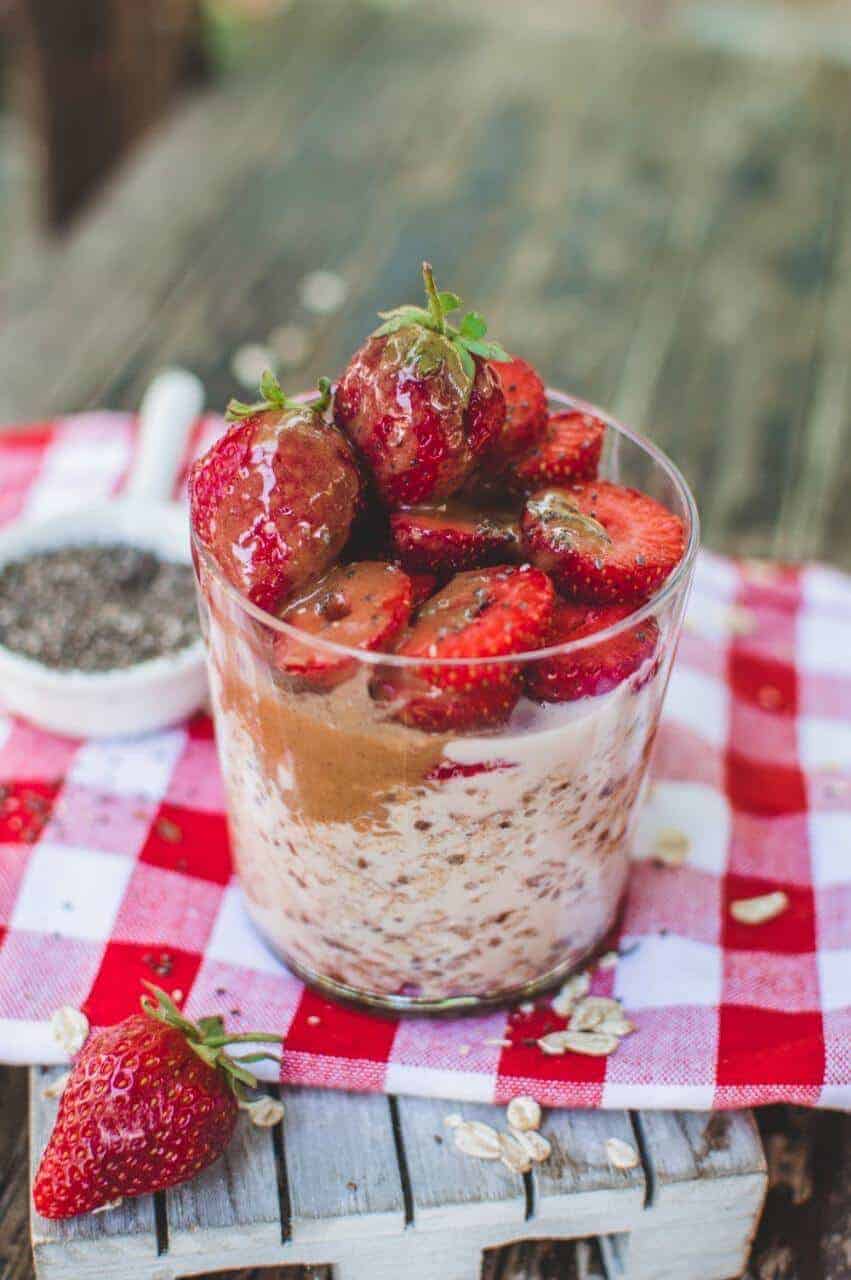Salted caramel poured over fresh strawberries on a jar of overnight oats.
