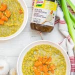 Two bowls of vegan split pea soup next to a jar of bouillon granules.