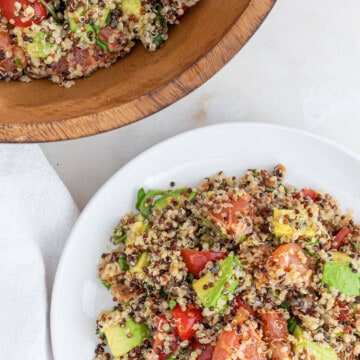 Tanzanian Quinoa Salad on a white plate next to a wood serving bowl.