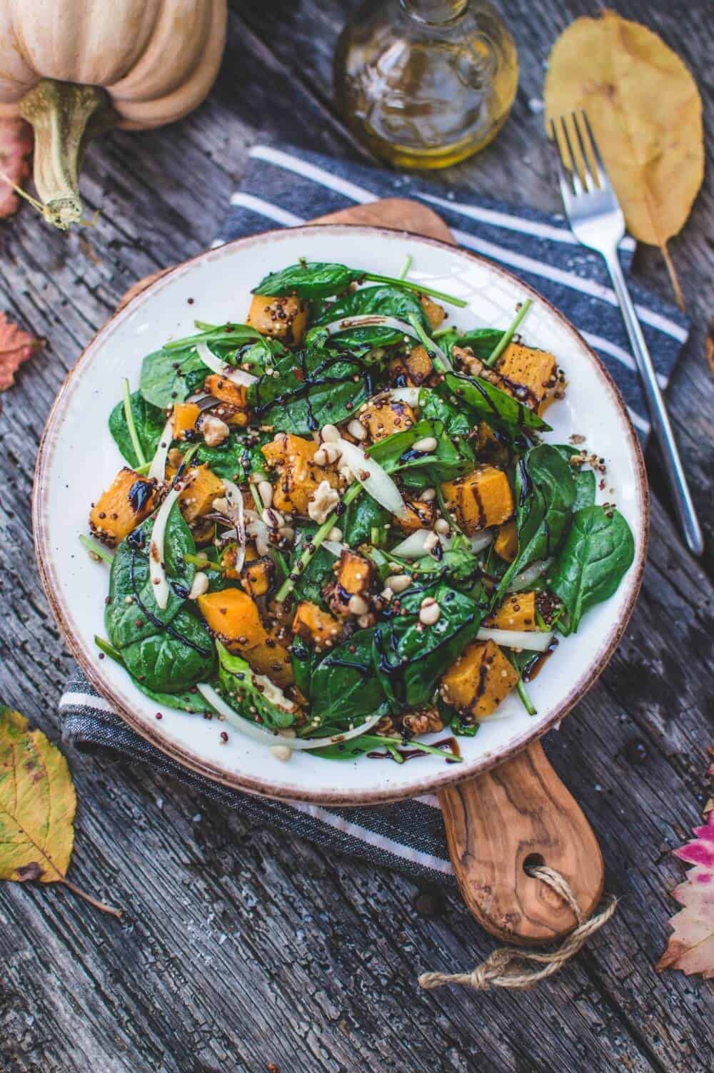 Perfect fall spinach salad in a large white serving bowl.