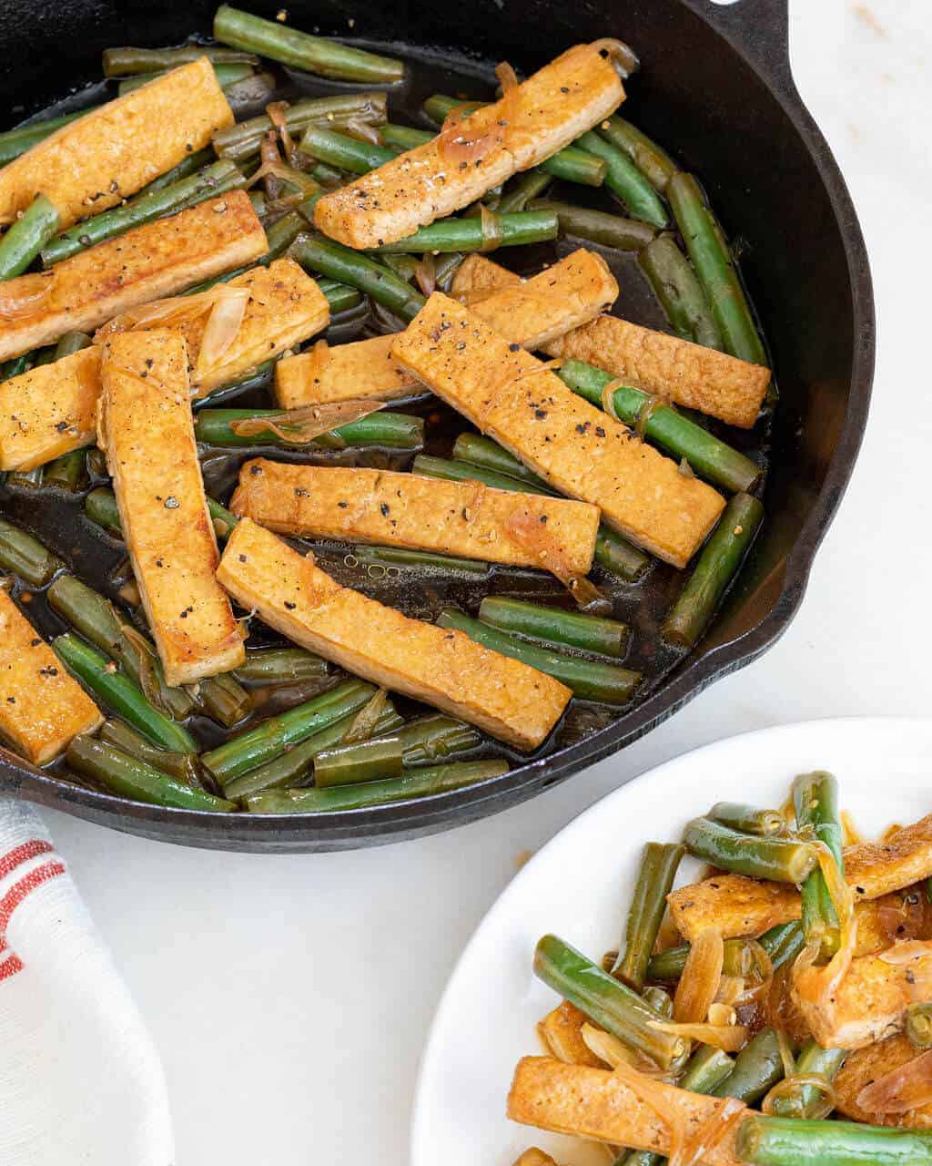 Cast iron skillet of lime tofu strips and green beans.