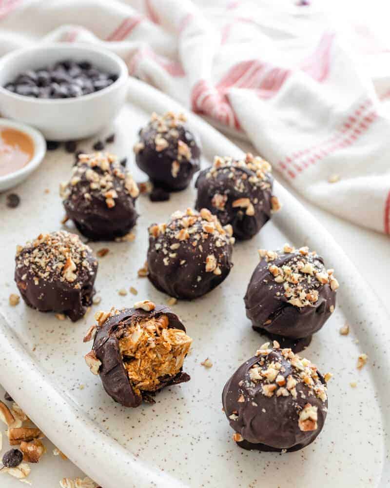 Chocolate covered peanut butter trail mix balls on a white platter.