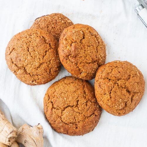 Triple Ginger cookies piled on a white marble background.