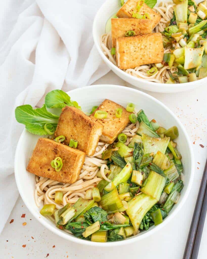 White bowl with spicy tofu and udon noodles.