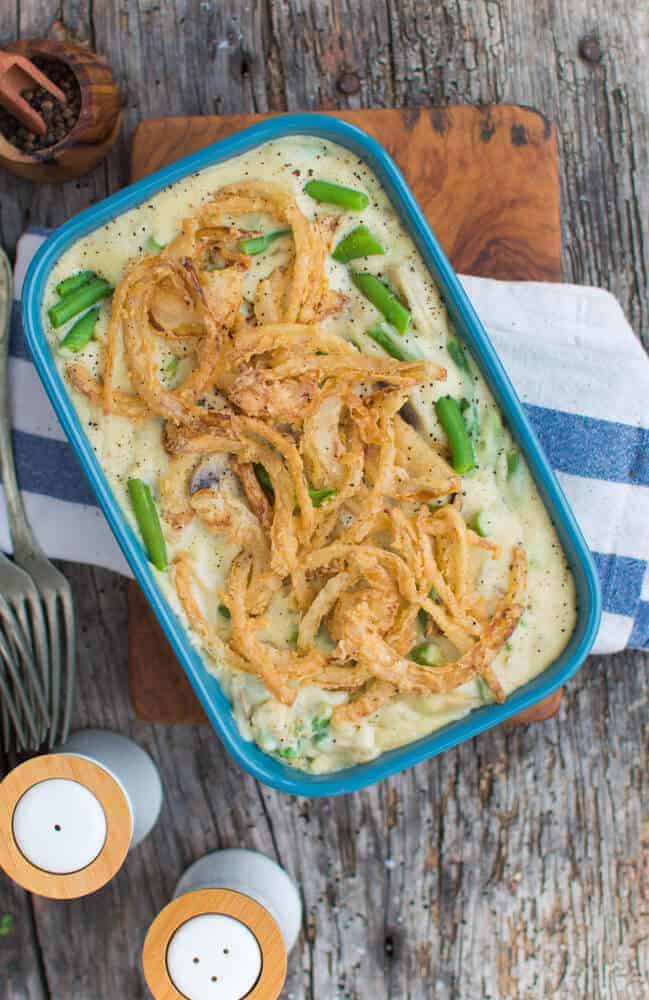 finished green bean casserole in a blue dish against a dark gray wood background