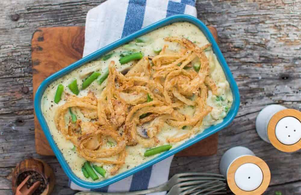 finished green bean casserole dish in a blue tray against a gray. background