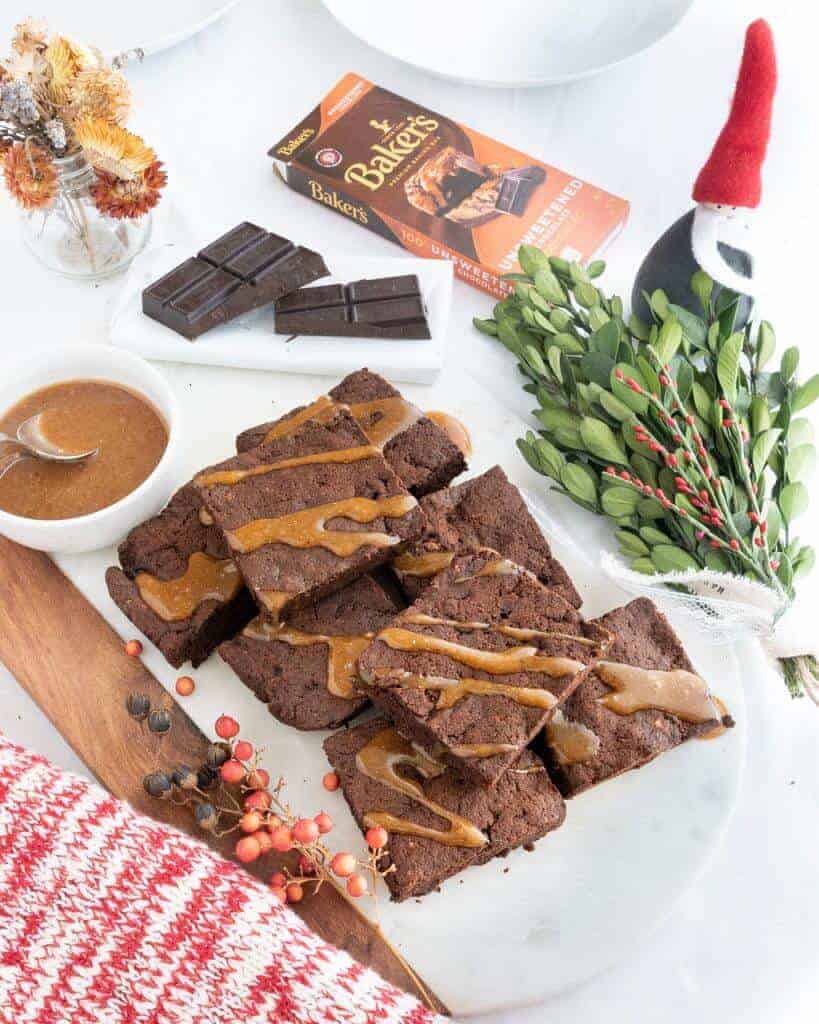 Caramel drizzled brownies on a white marble board.