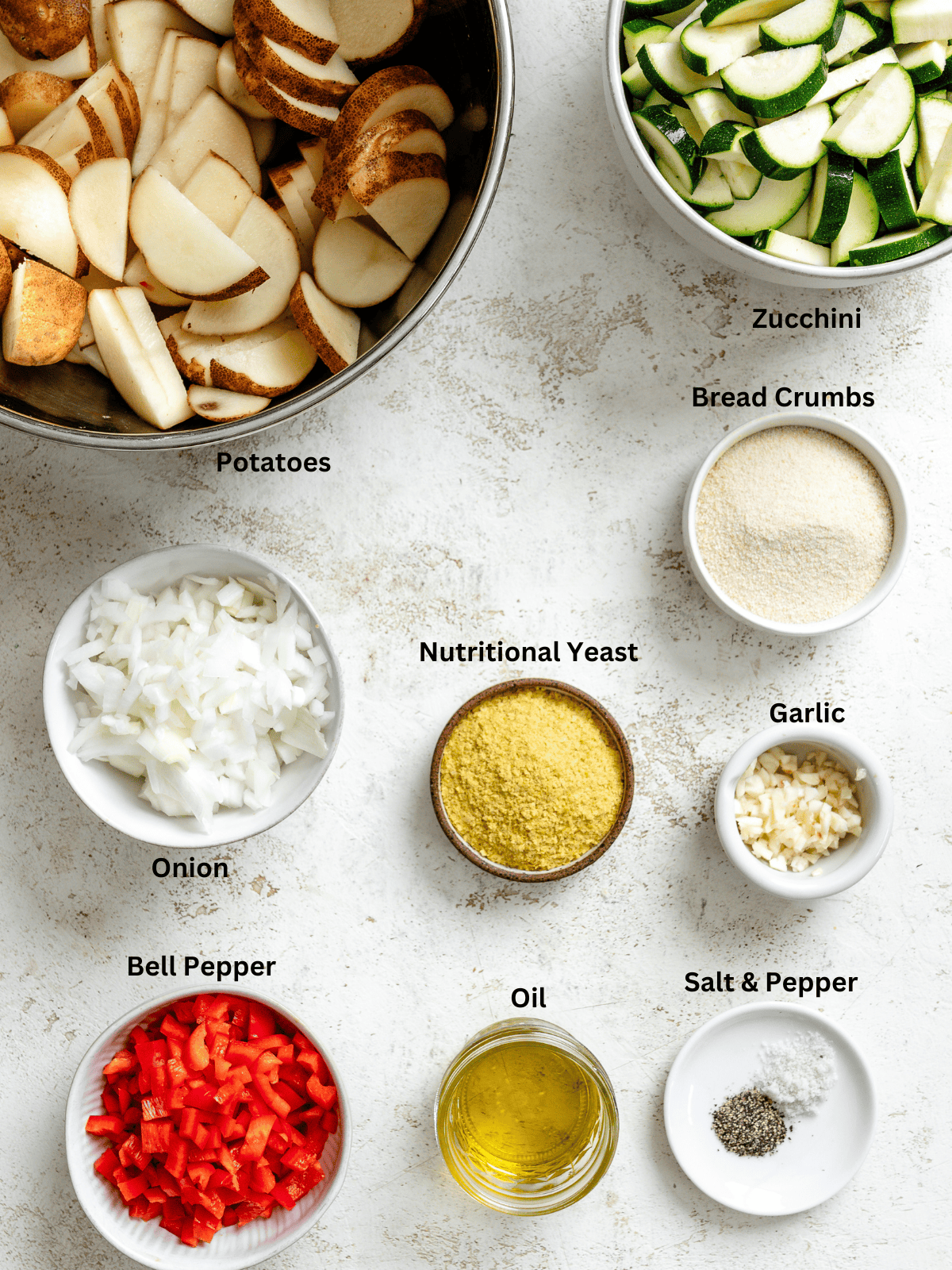 Ingredients for Zucchini Potato Bake measured out on a white surface.