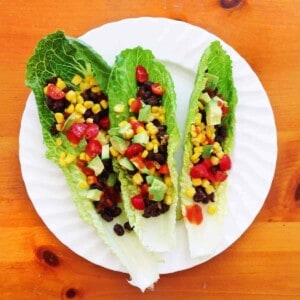 Almost raw tacos in lettuce leaves on a white plate.