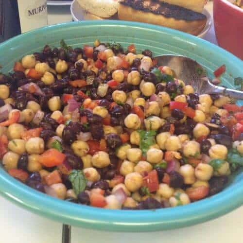 Blue oblong bowl with a serving spoon in mixed bean salad.