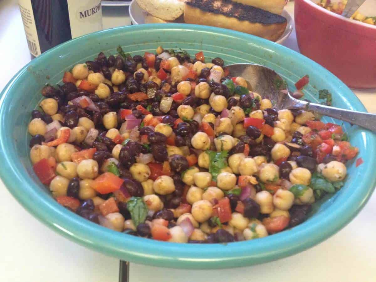 Blue oblong bowl with a serving spoon in mixed bean salad.