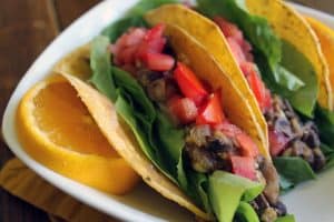 Black bean and orange breakfast taco on a plate with sliced oranges.