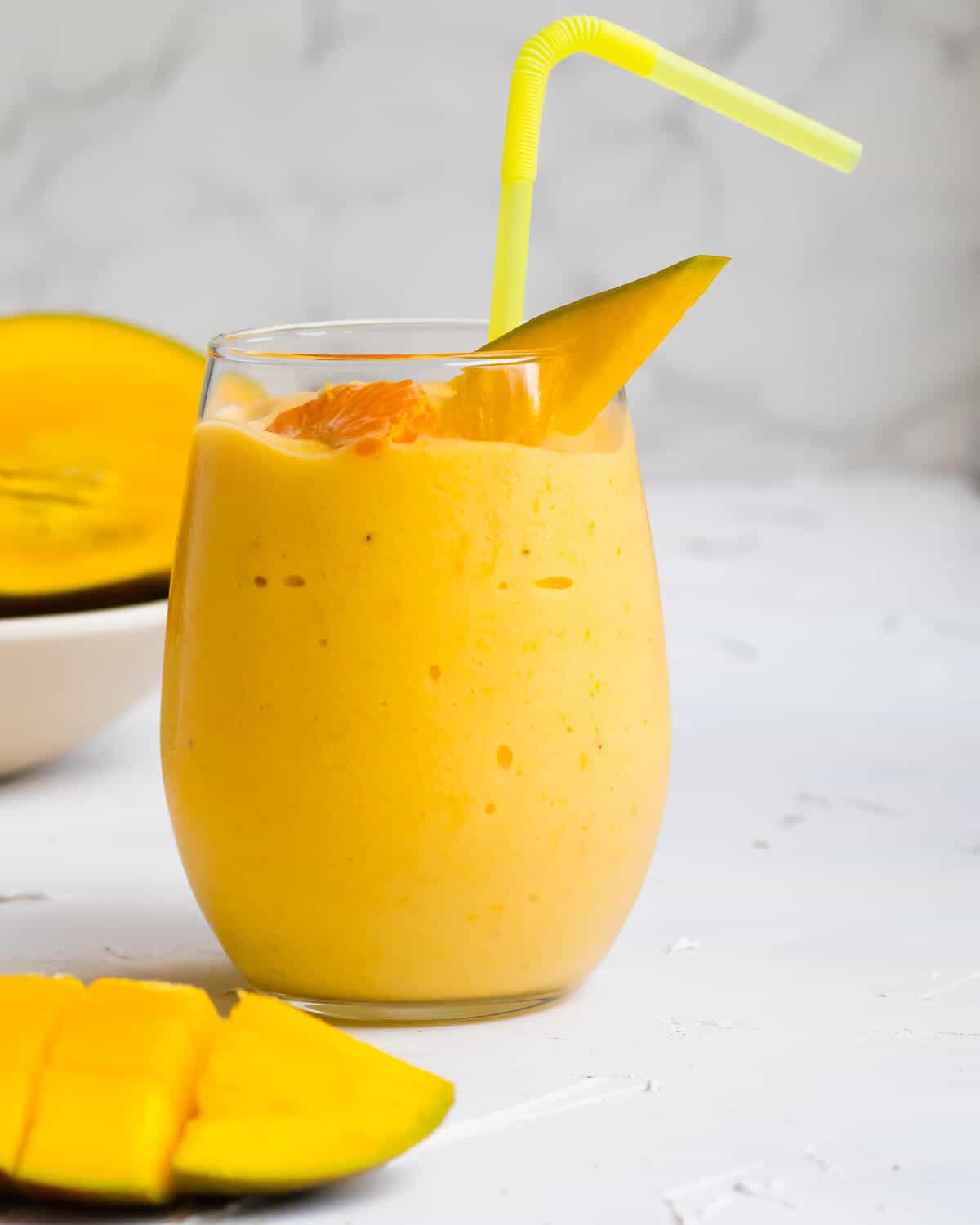 Citrus mango smoothie in a glass with a bendy straw.