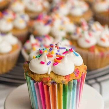 several confetti cupcakes with rainbow cupcake sleeves in a white background
