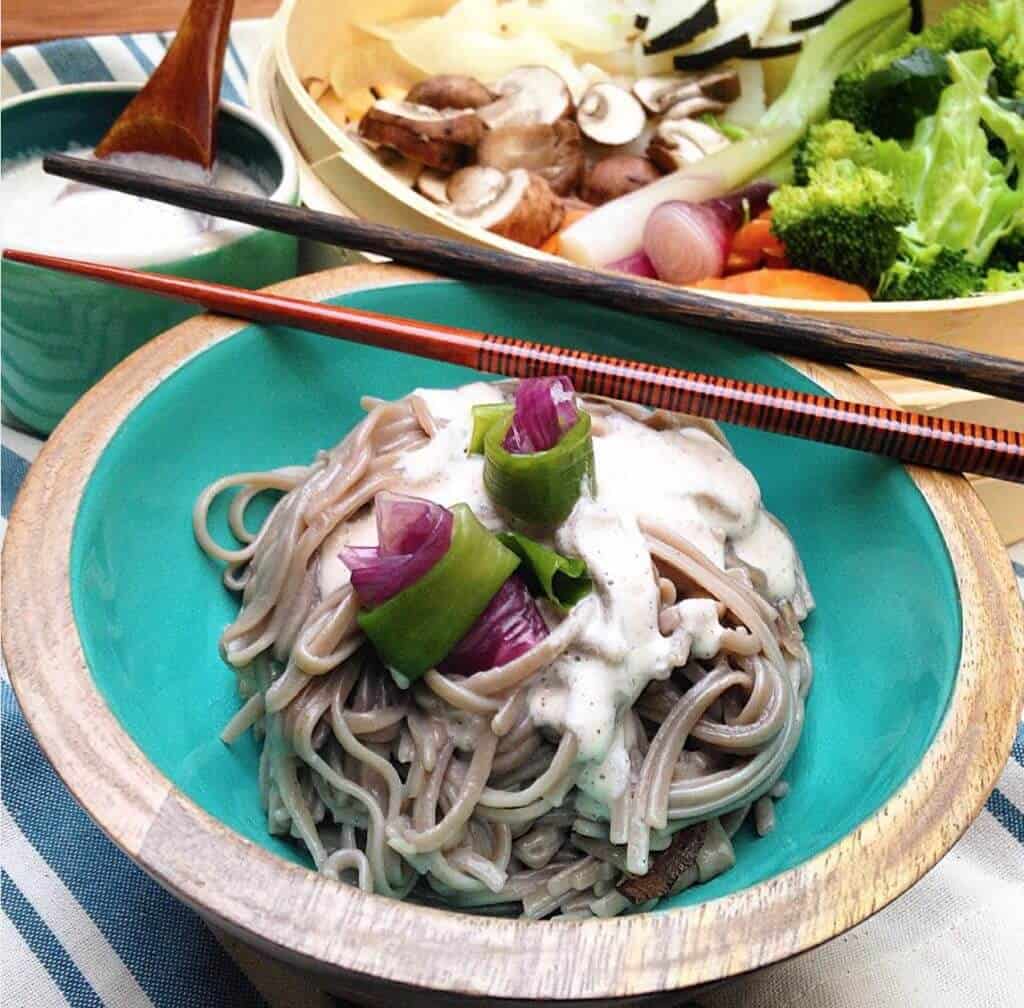 Creamy five minute garlic sauce over soba noodles with chopsticks in a bowl.