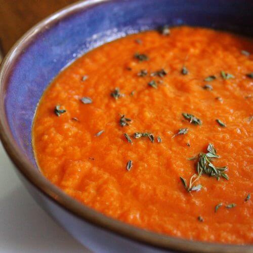 Blue bowl filled with creamy tomato thyme soup.