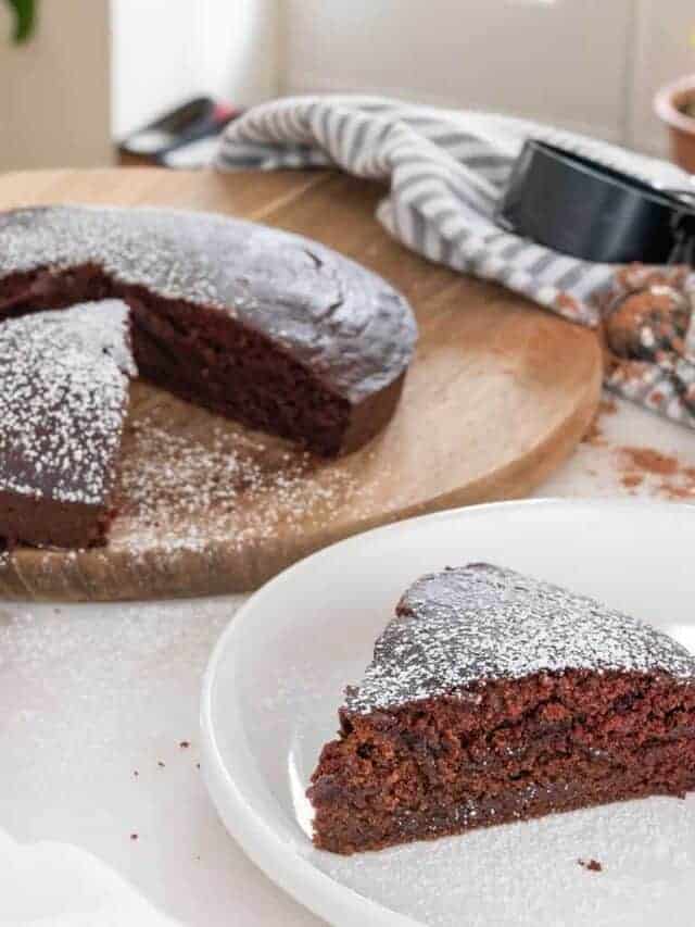 completed chocolate crazy cake with a slice plated in the forefront and the cake in the background on a brown platter