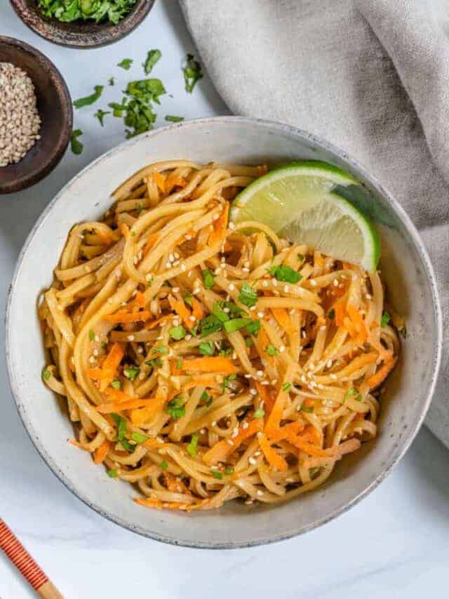 completed sesame noodle salad in a white bowl against a white background