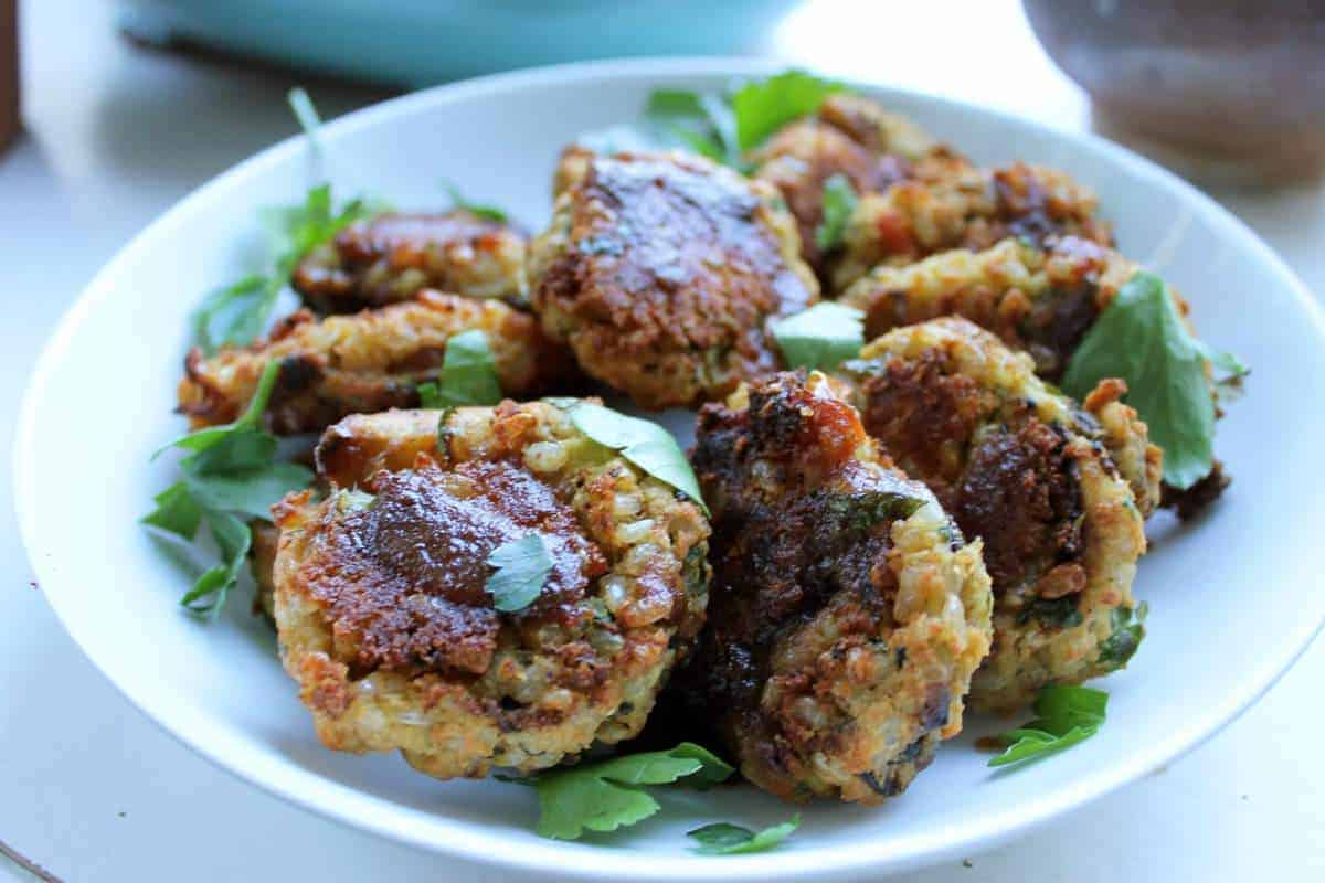 Vegan kicharri patties over a bed of greens on a plate.