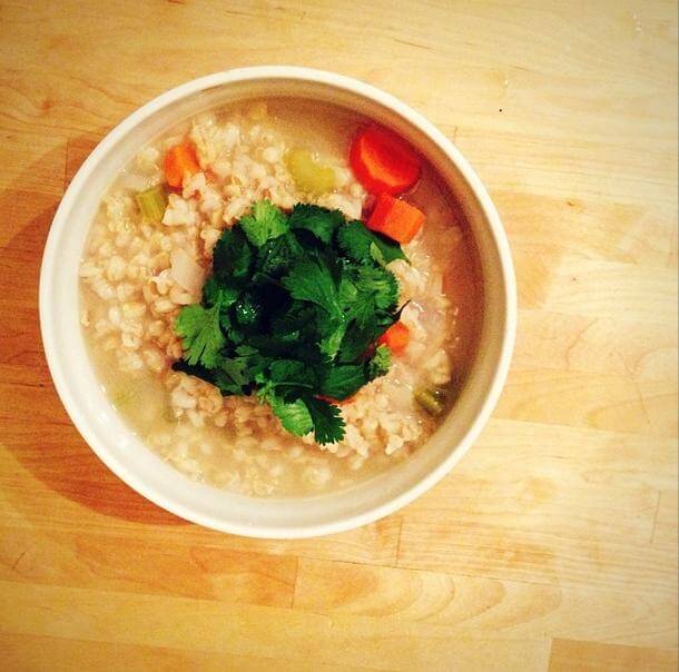 Barley and celery soup in a bowl topped with basil.