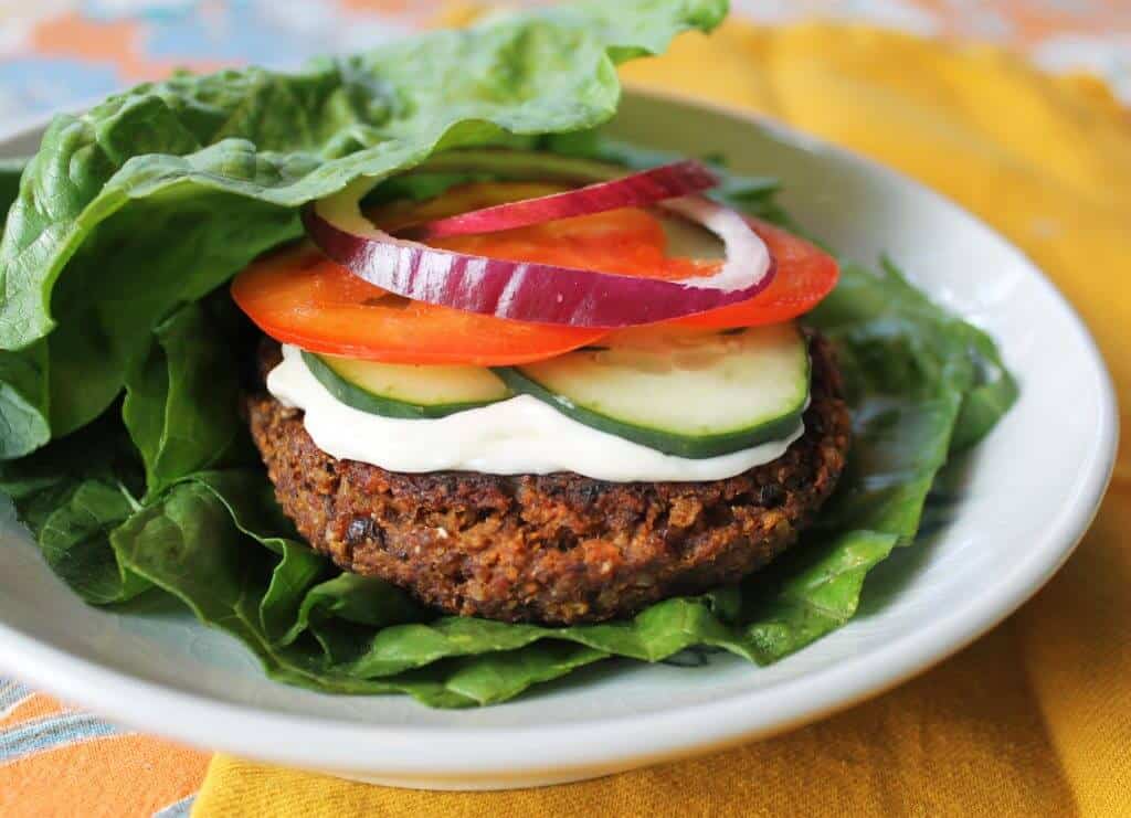 Lentil veggie burger with all the toppings on a bed of lettuce.